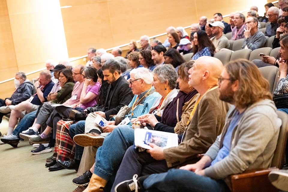 Audience members look to the front of the room