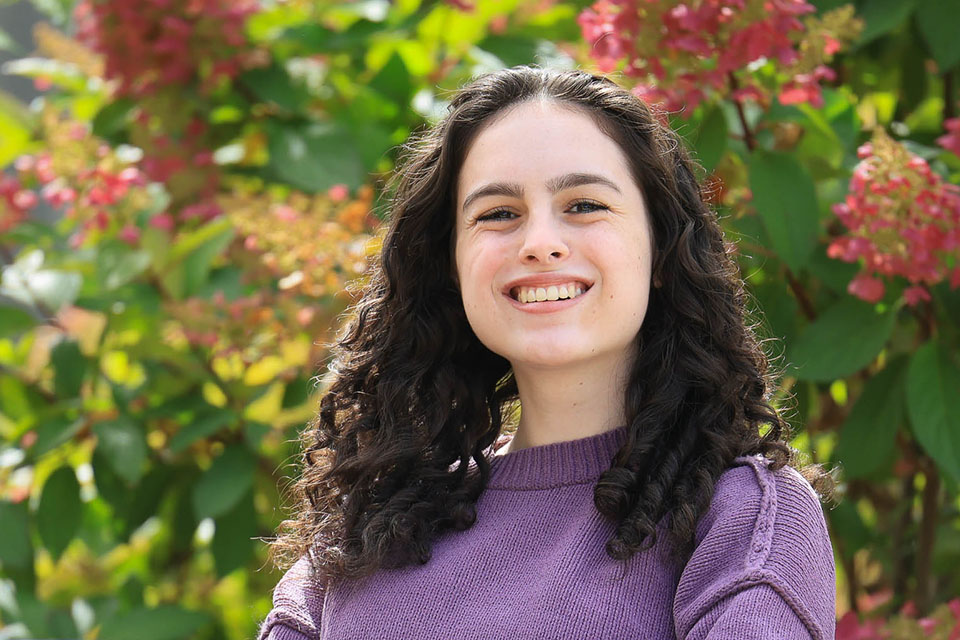 Mandy Feuerman '25 sits on a park bench