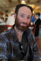 Headshot of Yaniv Feller inside wearing a blue plaid shirt