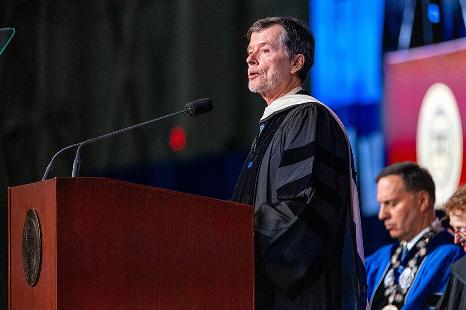 Ken Burns speaking at a podium at the undergraduate Commencement ceremony
