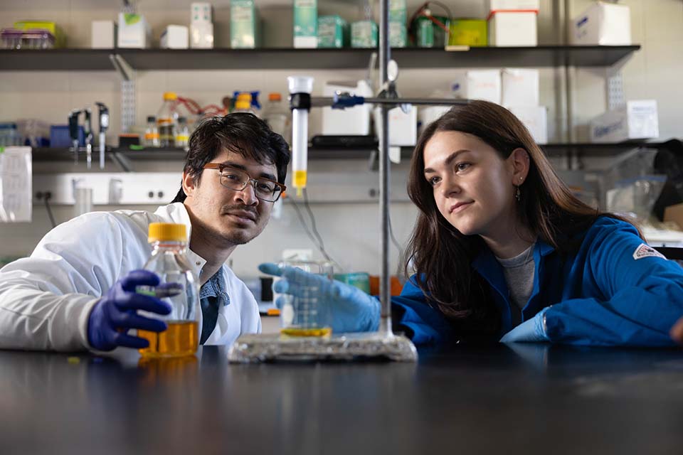 Two students work with science laboratory equipment.