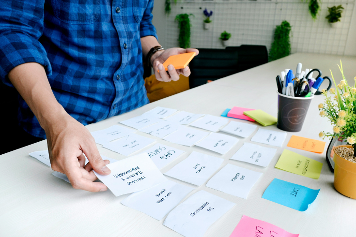 Person lining up notecards and sticky notes on a desk